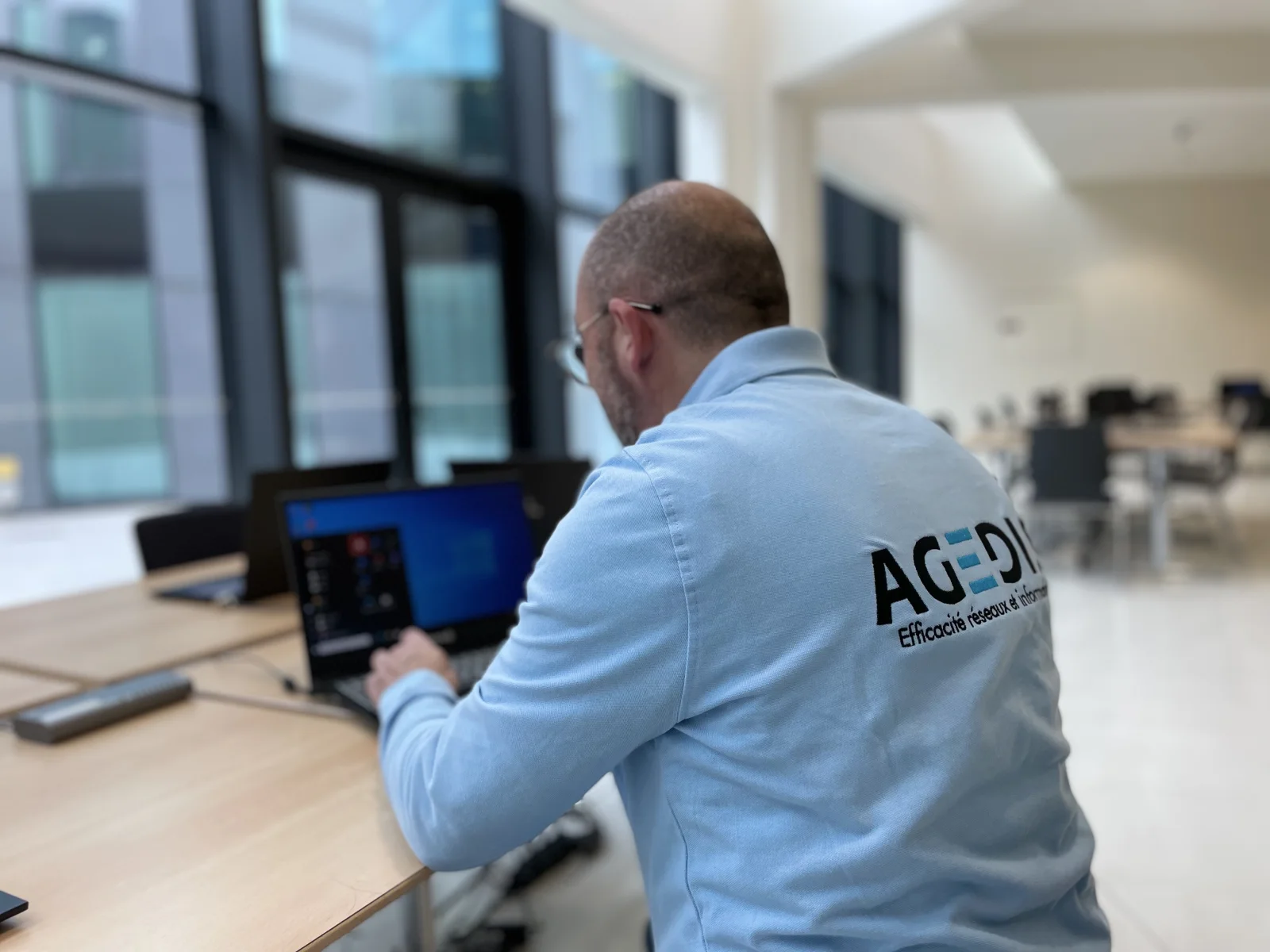 Intervenant Agedis vu de dos travaillant sur un portable.